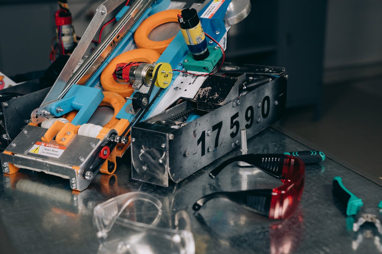 Detailed shot of a robotics machine with safety glasses and tools on metal surface.